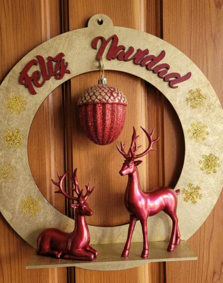 Corona navideña circular en madera MDF dorada con texto Feliz Navidad, dos renos rojos de resina sobre la repisa y adorno central de bellota